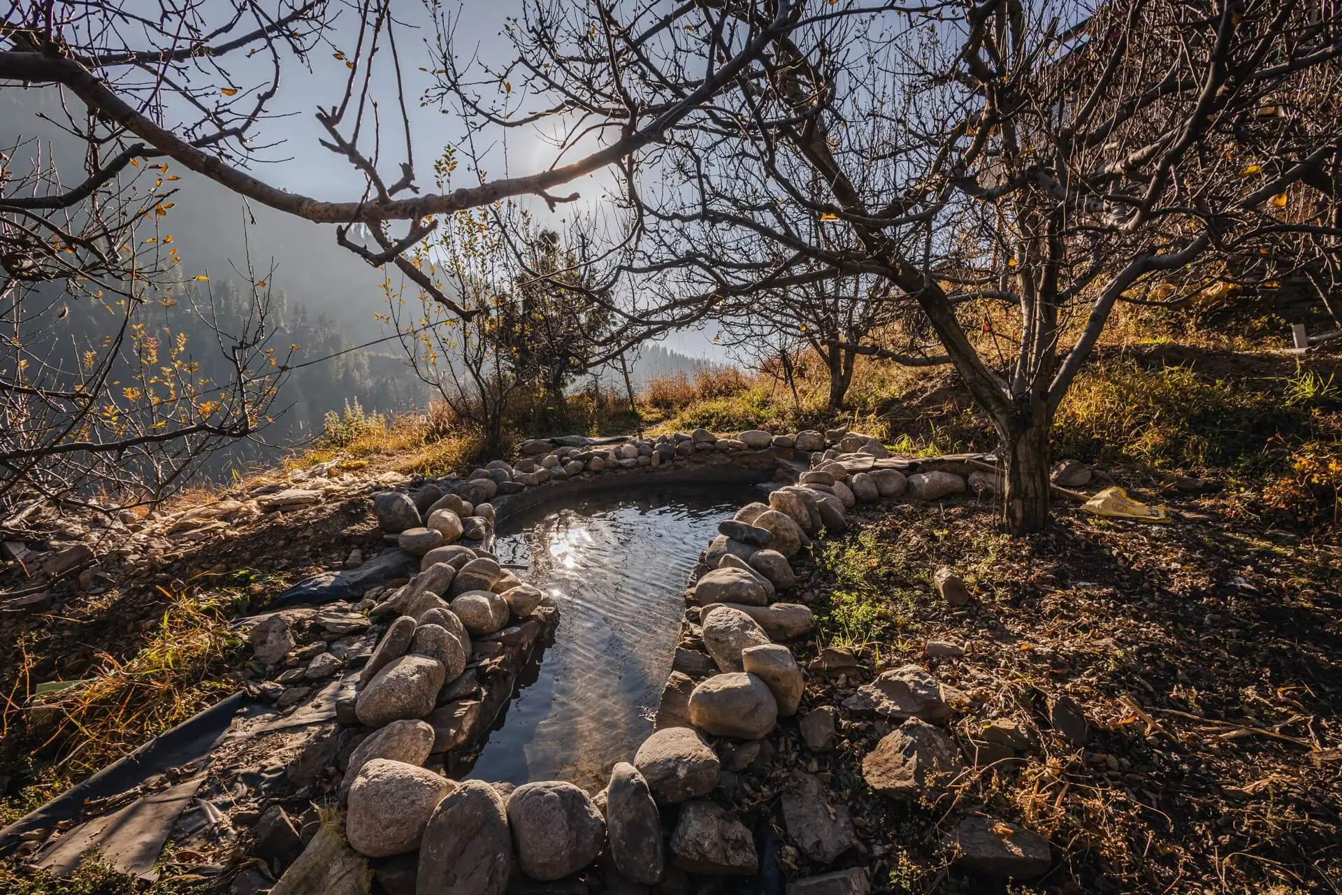 Wild's full stone-lined cold plunge among apple trees, with the valley beyond